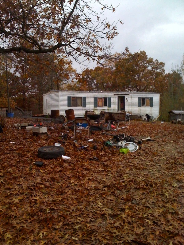 photo-3 A trailer back in the woods. These guys had rabbit cages, chickens, goat and donkeys running free too. And, they need to rake their yard.