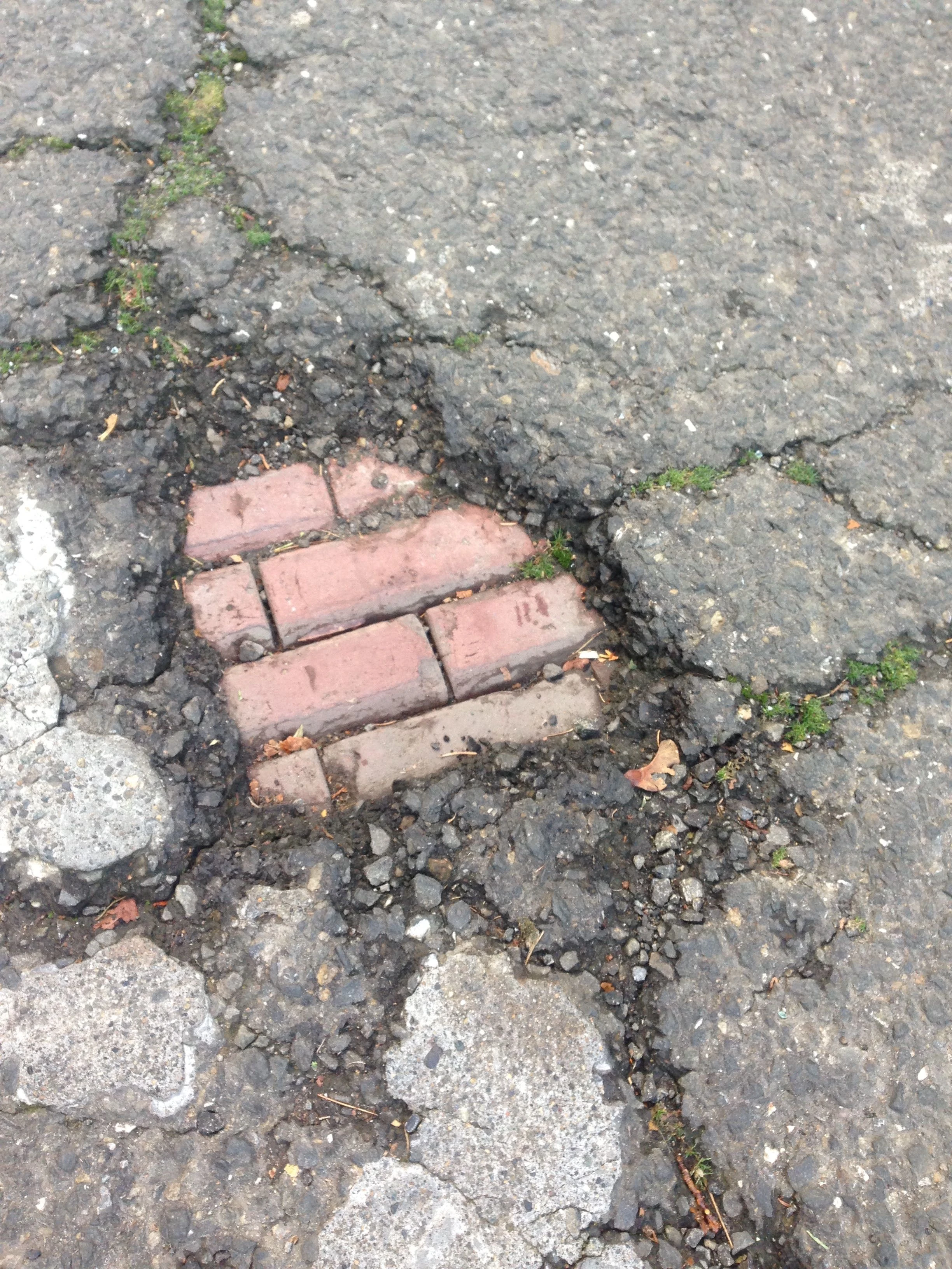I took a photo of this pothole in the asphalt. It&rsquo;s too bad they covered up the bricks.