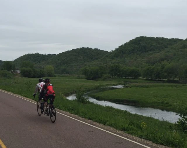 Kent and Trudi on the tandem riding through a valley.